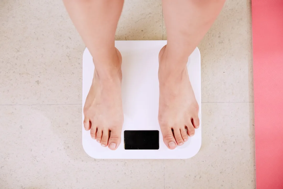 Person standing on a digital bathroom scale used for body weight tracking in pounds and kilograms